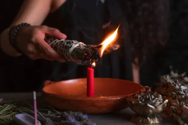 Manos encendiendo un sahumerio de hierbas
